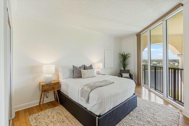 bedroom with access to outside, a textured ceiling, baseboards, and hardwood / wood-style flooring