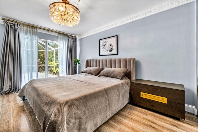 bedroom featuring ornamental molding, light hardwood / wood-style flooring, and a notable chandelier