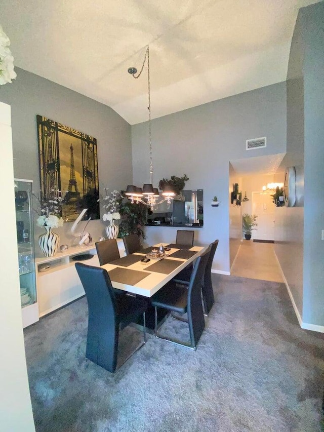 carpeted dining room featuring a chandelier and vaulted ceiling