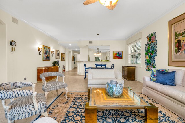 living room with ceiling fan with notable chandelier, ornamental molding, and light tile patterned floors