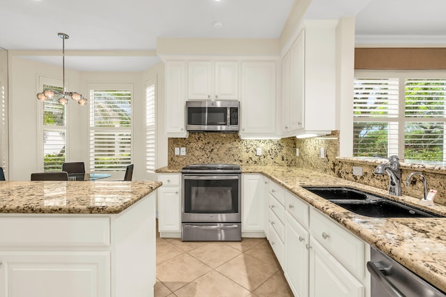 kitchen with pendant lighting, appliances with stainless steel finishes, sink, and white cabinetry