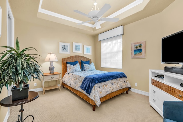 bedroom with light carpet, crown molding, ceiling fan, and a tray ceiling