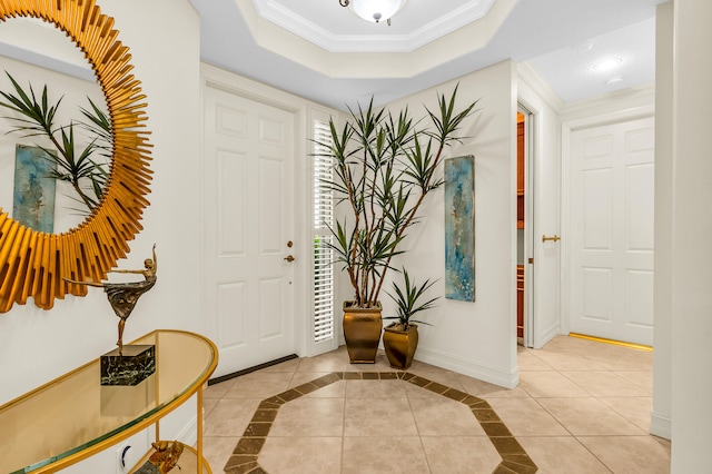 tiled foyer entrance with a tray ceiling and ornamental molding