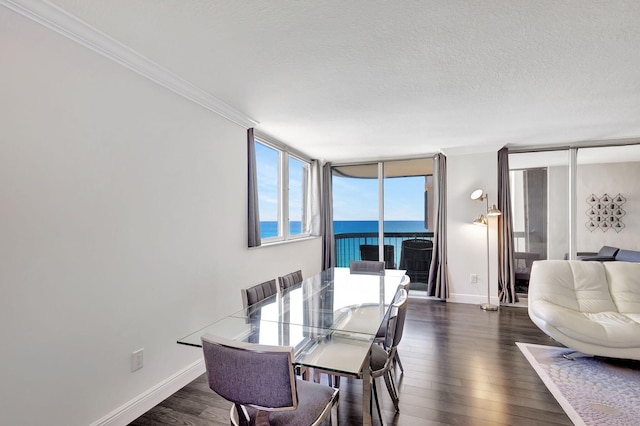 dining area with a textured ceiling, ornamental molding, expansive windows, a water view, and dark wood-type flooring