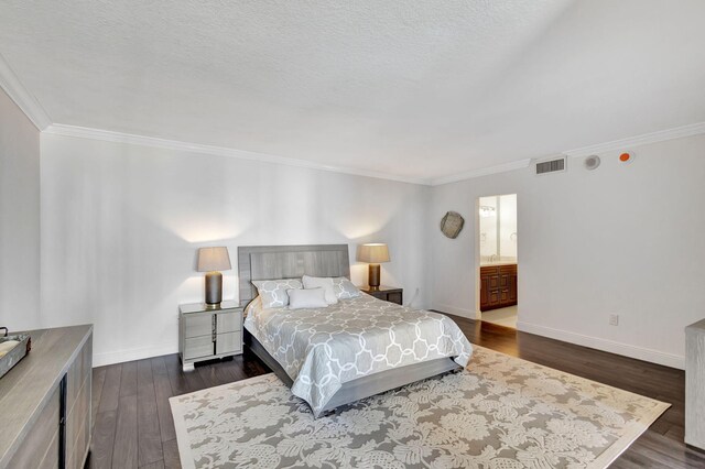 bedroom featuring dark hardwood / wood-style flooring, ornamental molding, a textured ceiling, and ensuite bath