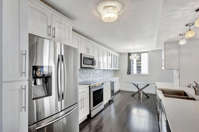 kitchen with white cabinetry, appliances with stainless steel finishes, dark wood-type flooring, and hanging light fixtures