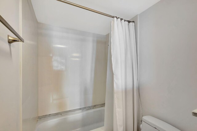 bathroom featuring toilet and shower / bathtub combination with curtain