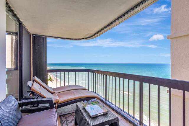 balcony featuring a water view and a beach view