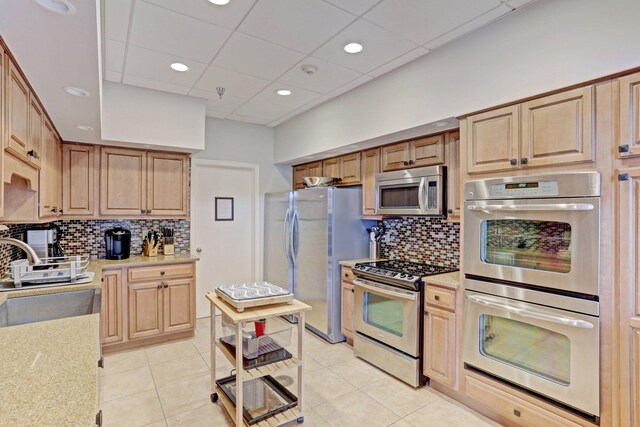 kitchen with sink, light stone countertops, appliances with stainless steel finishes, and light tile patterned flooring