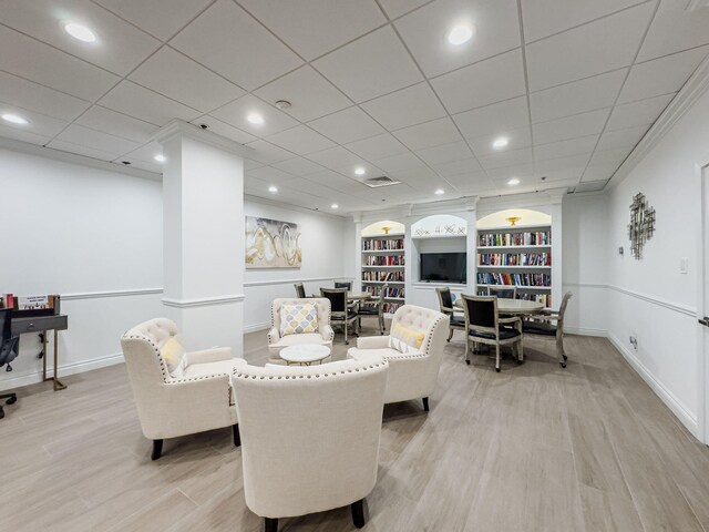 dining area with ornamental molding, a drop ceiling, light hardwood / wood-style flooring, and built in features