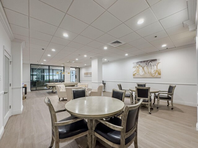 dining space with light hardwood / wood-style floors and a paneled ceiling