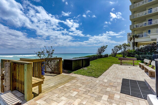 view of patio / terrace featuring a deck with water view and a view of the beach