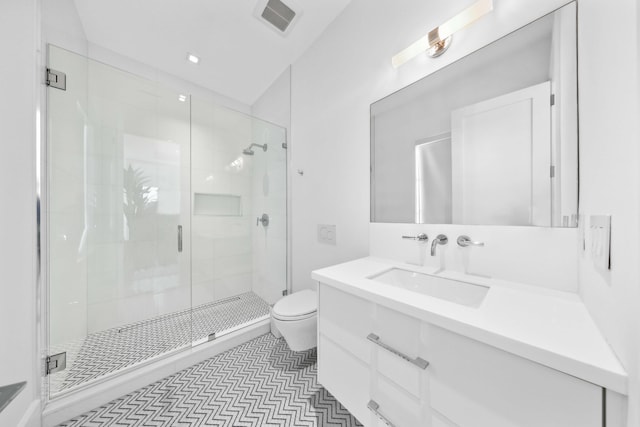 bathroom featuring tile patterned floors, vanity, toilet, and a shower with shower door