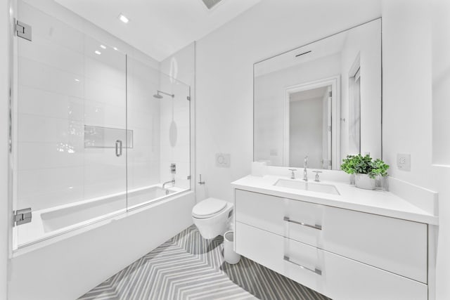 full bathroom featuring combined bath / shower with glass door, vanity, and toilet