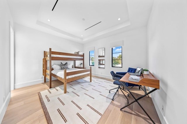 bedroom featuring light hardwood / wood-style flooring and a raised ceiling