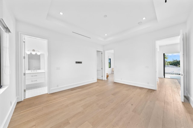 unfurnished room featuring light hardwood / wood-style flooring, a raised ceiling, and sink