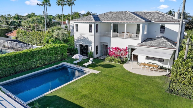 rear view of house featuring a balcony, a fenced in pool, a patio area, and a lawn