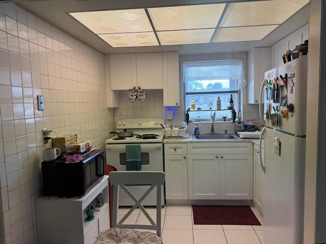 kitchen featuring a sink, light tile patterned flooring, white appliances, light countertops, and white cabinetry