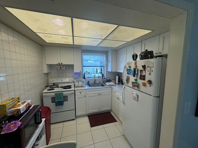 kitchen with light tile patterned flooring, sink, white appliances, white cabinetry, and decorative backsplash