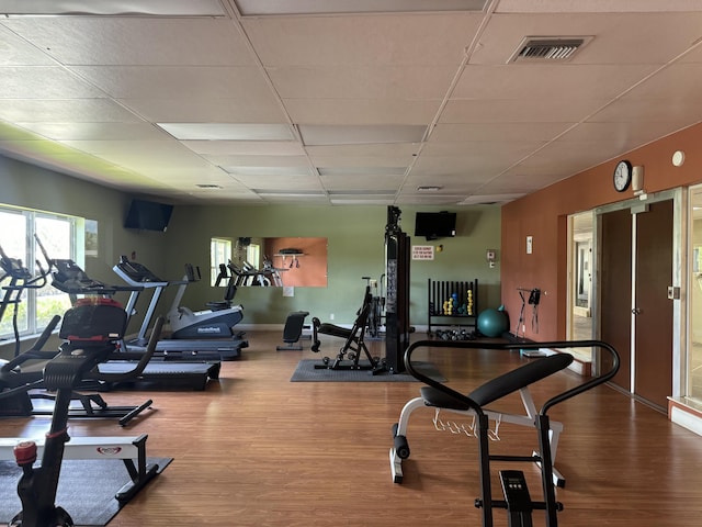 workout area featuring baseboards, wood finished floors, visible vents, and a drop ceiling