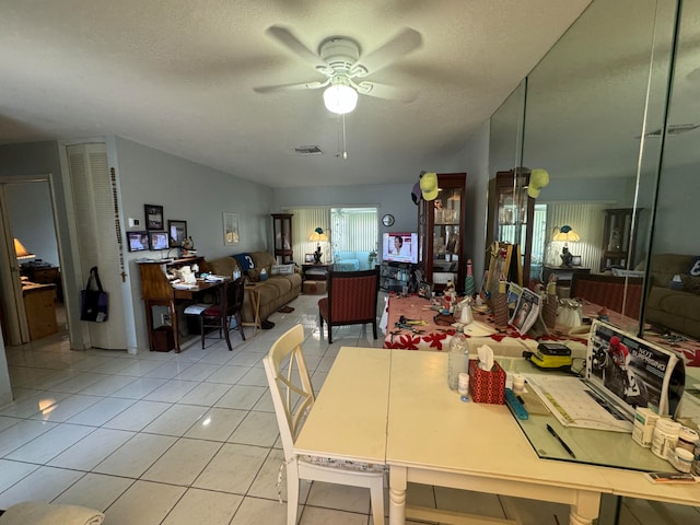 dining space with a textured ceiling, light tile patterned floors, and ceiling fan