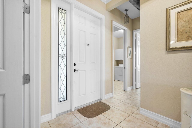 tiled foyer entrance with washer / dryer