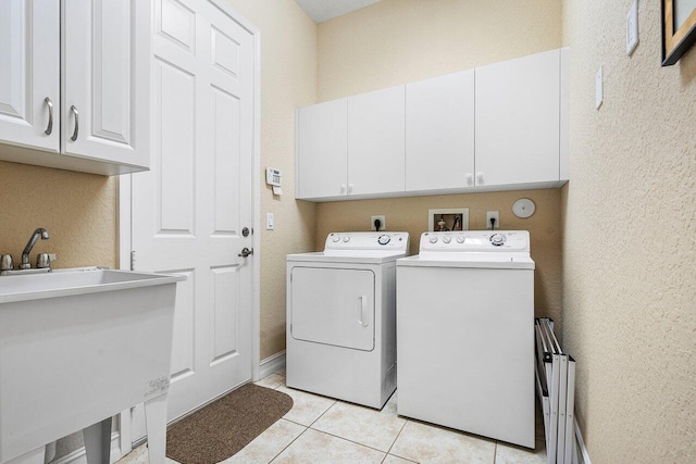 clothes washing area with light tile patterned flooring, cabinets, independent washer and dryer, and sink