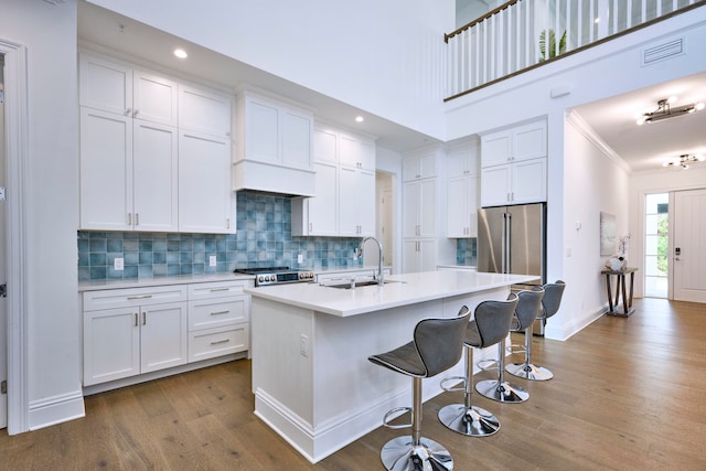 kitchen featuring sink, white cabinets, and an island with sink