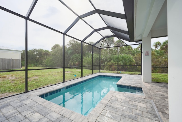 view of swimming pool featuring a lawn, a patio, and glass enclosure