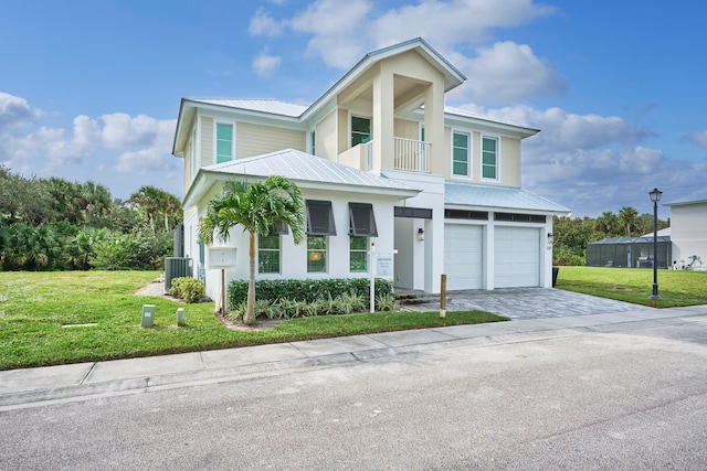 view of front of home featuring a front lawn, central AC, a garage, and a balcony