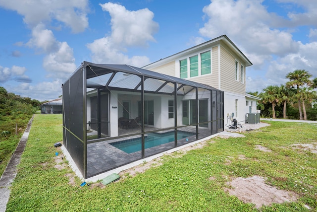 rear view of house with a patio area, glass enclosure, central AC unit, and a lawn