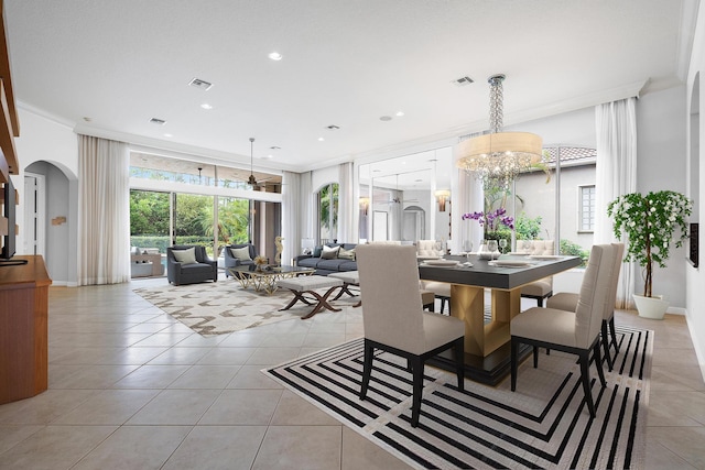 dining space with light tile patterned flooring, ornamental molding, and an inviting chandelier