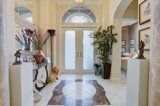 entrance foyer featuring a high ceiling, ornamental molding, french doors, and light tile patterned floors