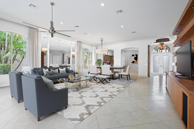 living room with light tile patterned flooring, ceiling fan with notable chandelier, and crown molding