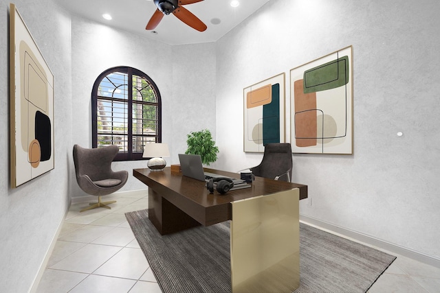 home office with ceiling fan, a towering ceiling, and light tile patterned floors