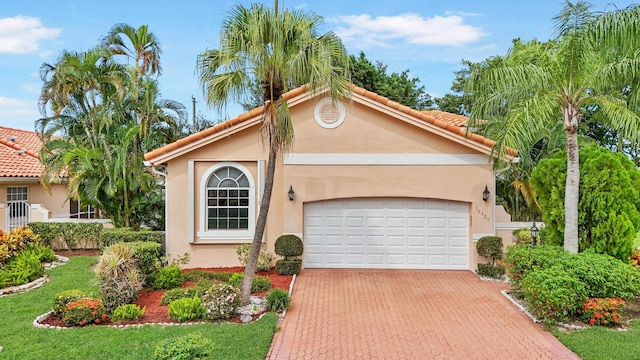 mediterranean / spanish-style house featuring a front yard and a garage