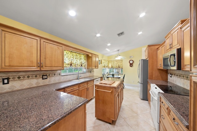 kitchen featuring appliances with stainless steel finishes, sink, a kitchen island, backsplash, and light tile patterned floors