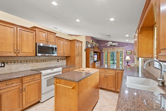 kitchen featuring sink, a center island, dark stone countertops, white electric range oven, and light tile patterned floors