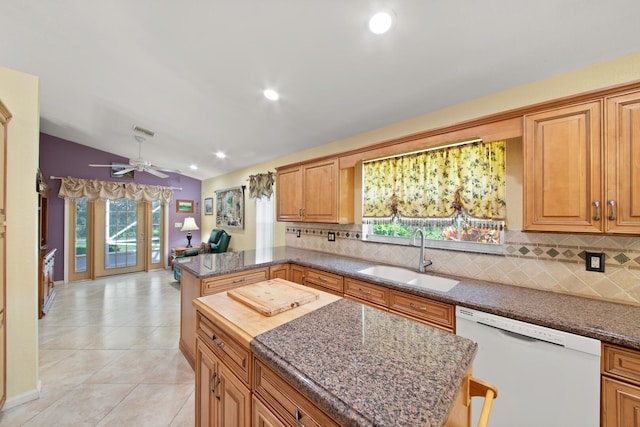 kitchen featuring white dishwasher, vaulted ceiling, sink, plenty of natural light, and a center island