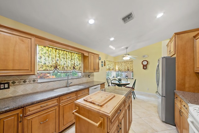 kitchen with decorative backsplash, ceiling fan, a kitchen island, sink, and white appliances