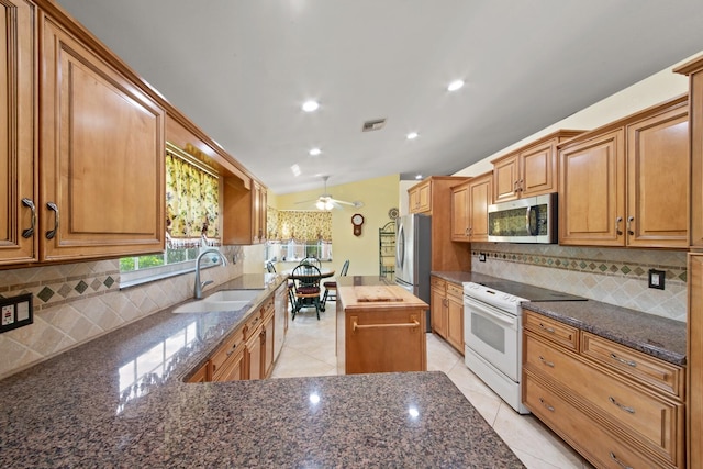 kitchen featuring decorative backsplash, dark stone countertops, sink, a center island, and appliances with stainless steel finishes