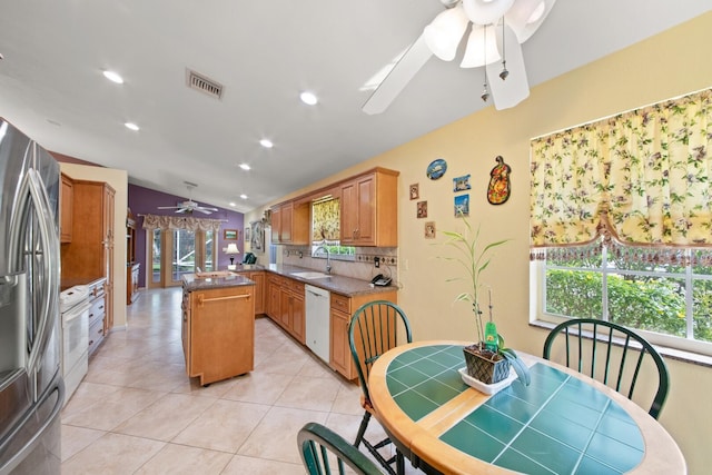 kitchen with white appliances, a center island, kitchen peninsula, lofted ceiling, and decorative backsplash