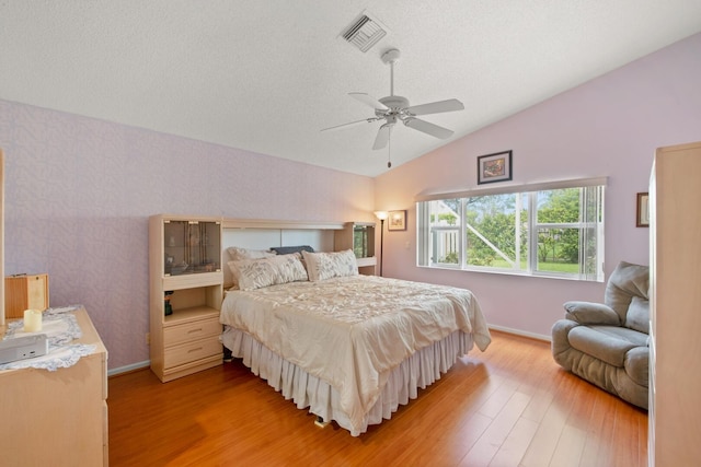 bedroom with ceiling fan, a textured ceiling, vaulted ceiling, and light wood-type flooring