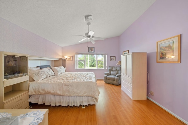 bedroom with ceiling fan, a textured ceiling, vaulted ceiling, and light wood-type flooring