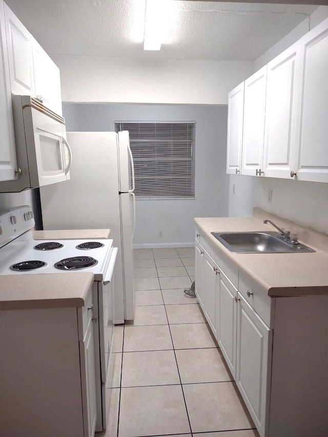 kitchen featuring light tile patterned flooring, white appliances, sink, and white cabinetry