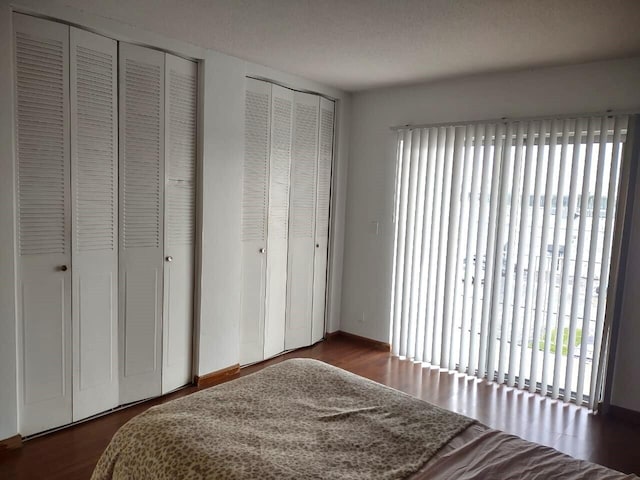 bedroom with multiple closets, a textured ceiling, and dark hardwood / wood-style flooring