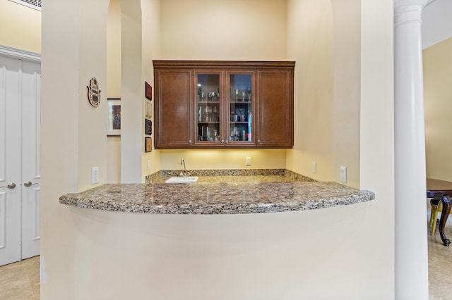 bar featuring light stone counters and sink