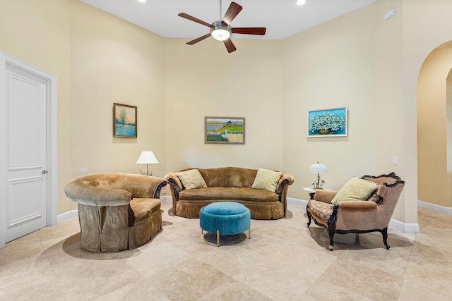 living room with a towering ceiling and ceiling fan