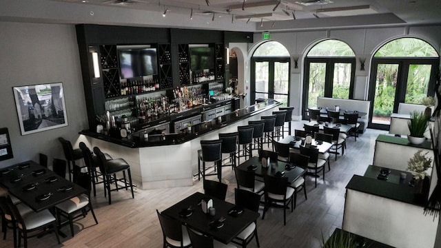 bar featuring french doors, rail lighting, and hardwood / wood-style floors