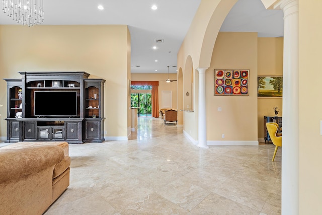 living room featuring ceiling fan with notable chandelier and ornate columns